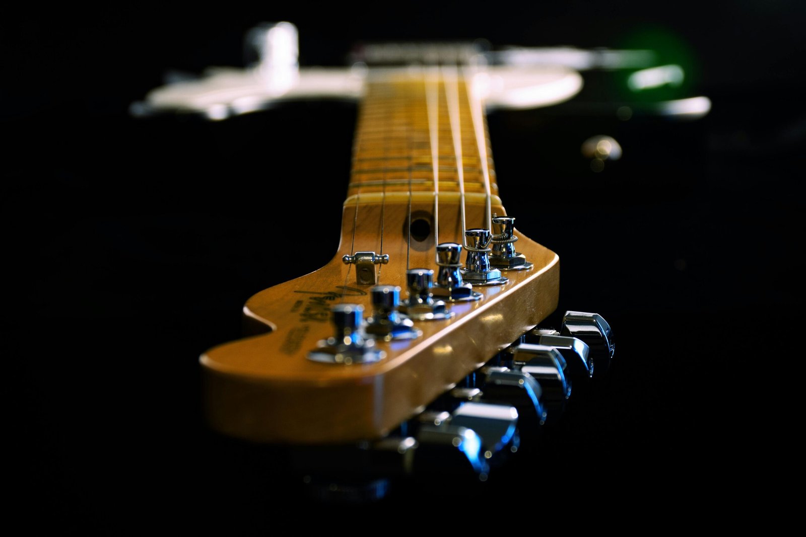 Artistic close-up of an electric guitar showing strings and tuners, highlighting depth and craftsmanship.